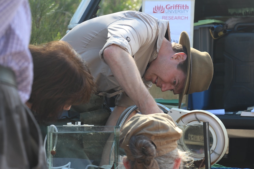 A man in a slide and a wide-brimmed hat with his hand bent in a tank